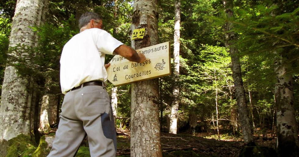 homme fixant un panneau de balisage dans la forêt de l'Hospice de France